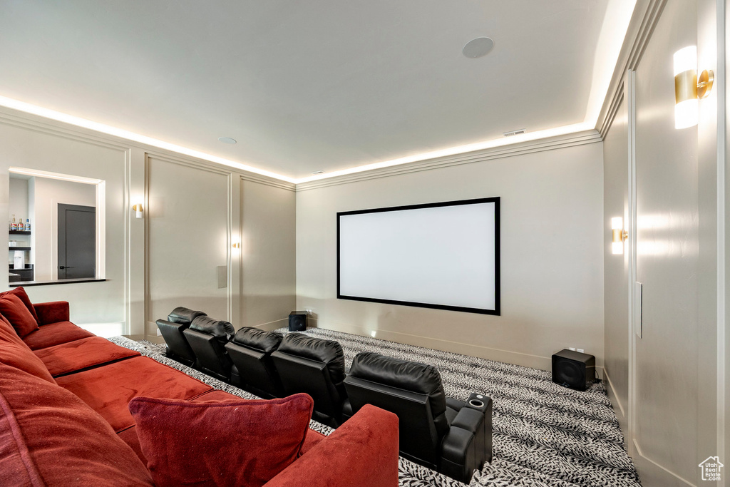 Carpeted home theater room featuring crown molding and baseboards