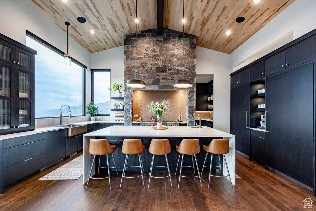 Kitchen with light countertops, wood ceiling, an island with sink, and a sink