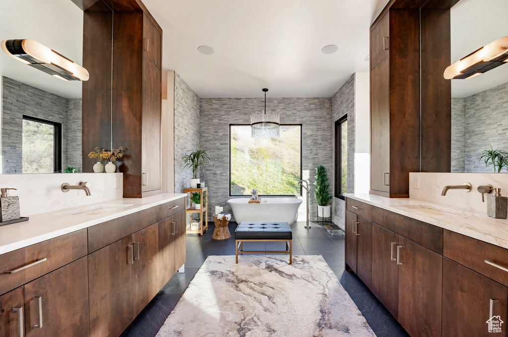 Full bath featuring a soaking tub, two vanities, and a sink