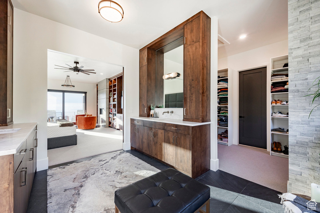 Full bathroom featuring two vanities, a spacious closet, tile patterned flooring, and ceiling fan
