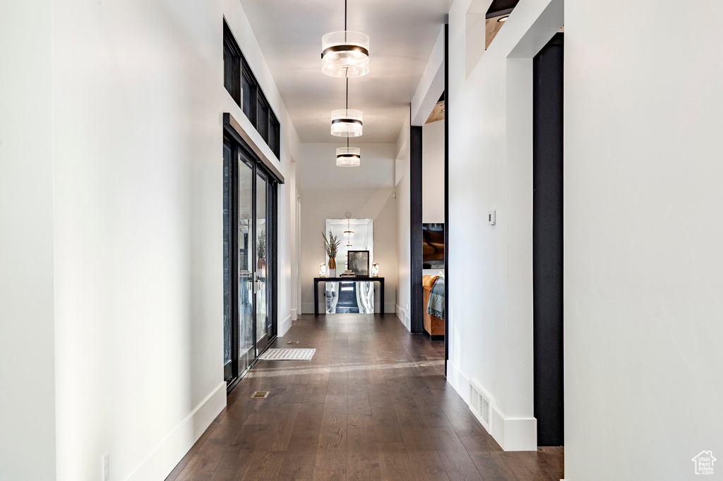 Hall featuring dark wood-style flooring, baseboards, and visible vents