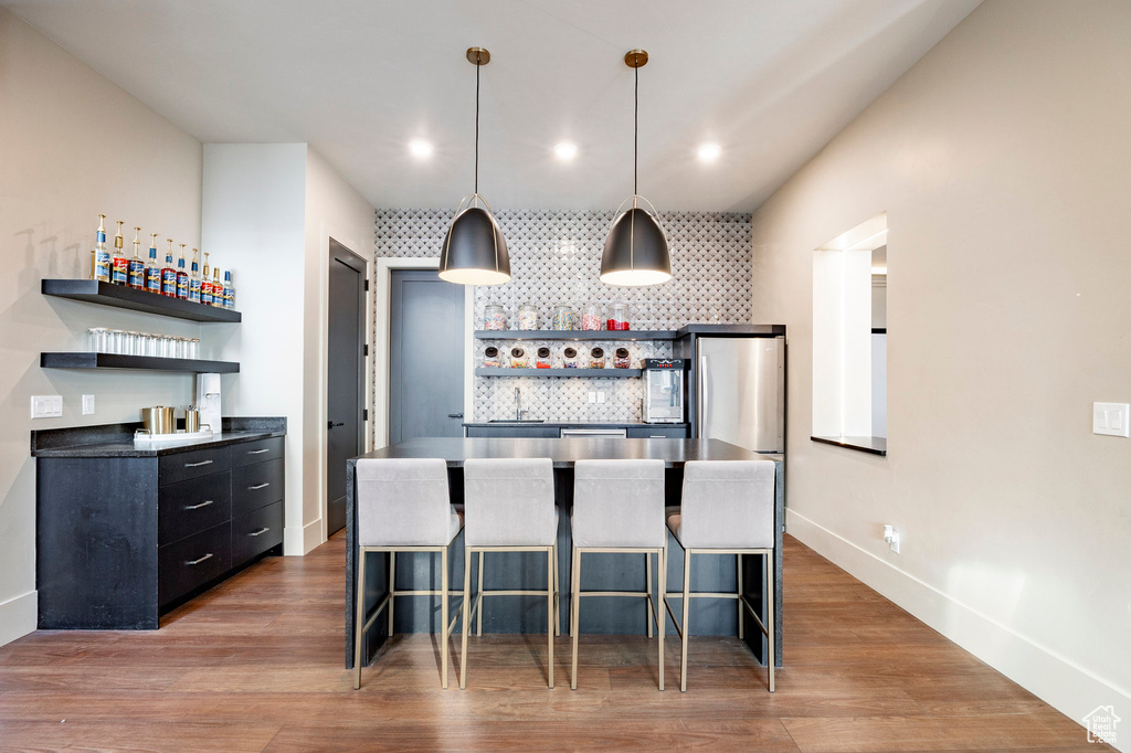 Kitchen with backsplash, dark cabinets, open shelves, and a breakfast bar area