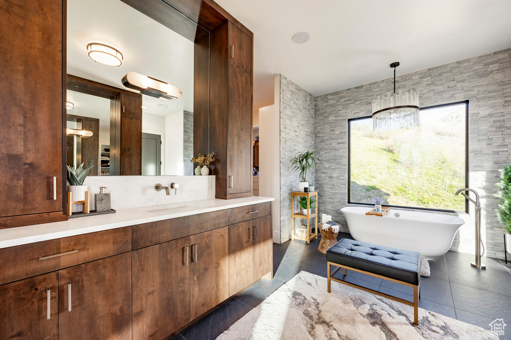 Bathroom featuring vanity, a notable chandelier, and a soaking tub