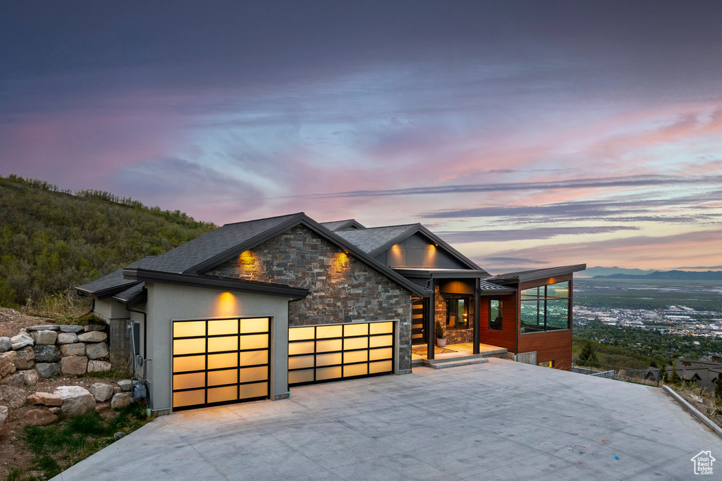 Contemporary house featuring stone siding, stucco siding, an attached garage, and driveway