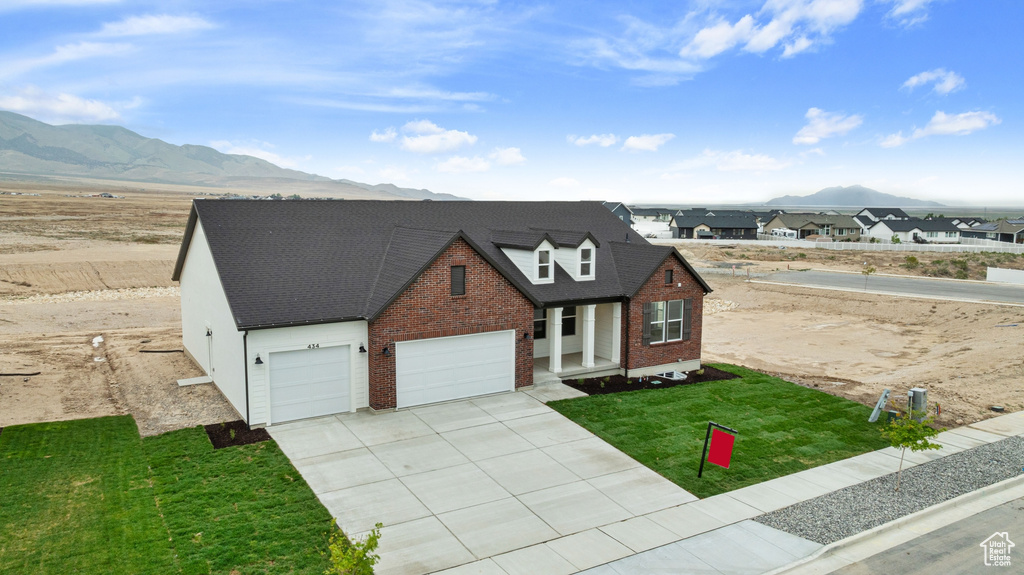 Traditional home with a mountain view, a garage, a front yard, brick siding, and driveway