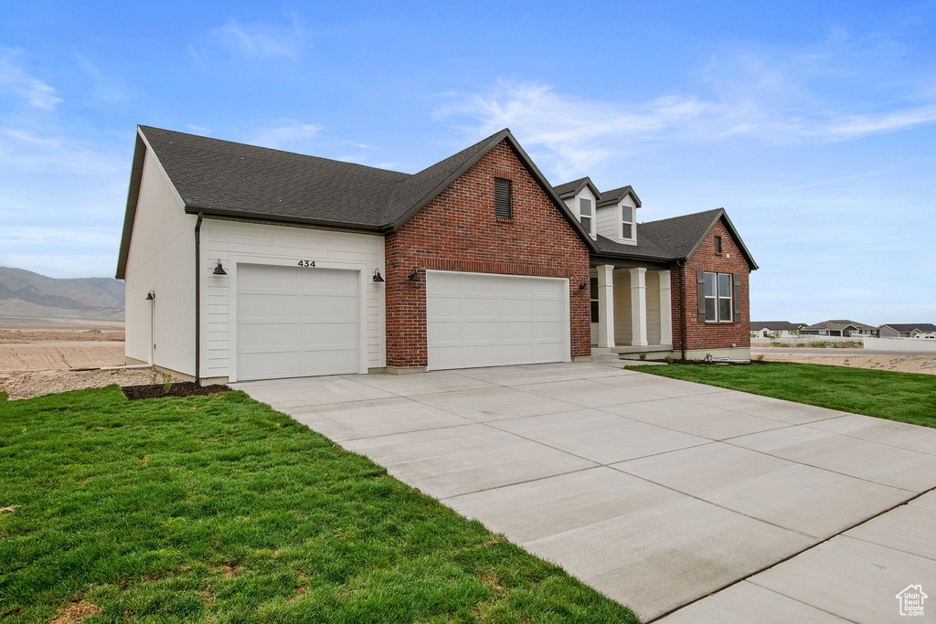 View of front of home featuring driveway, brick siding, a garage, roof with shingles, and a front lawn