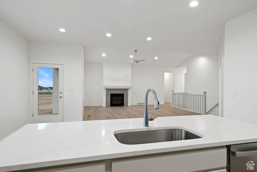 Kitchen featuring light wood finished floors, a sink, open floor plan, light stone counters, and recessed lighting