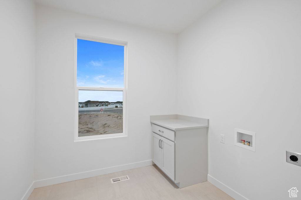 Clothes washing area featuring electric dryer hookup, cabinet space, washer hookup, visible vents, and baseboards