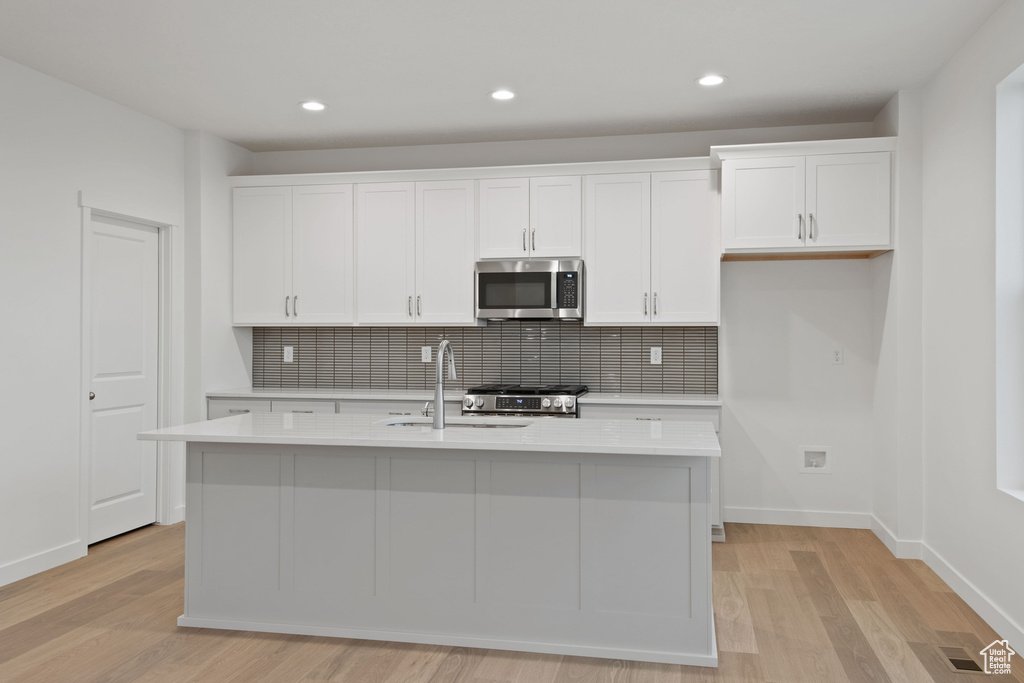 Kitchen with a sink, stainless steel appliances, light countertops, and white cabinets