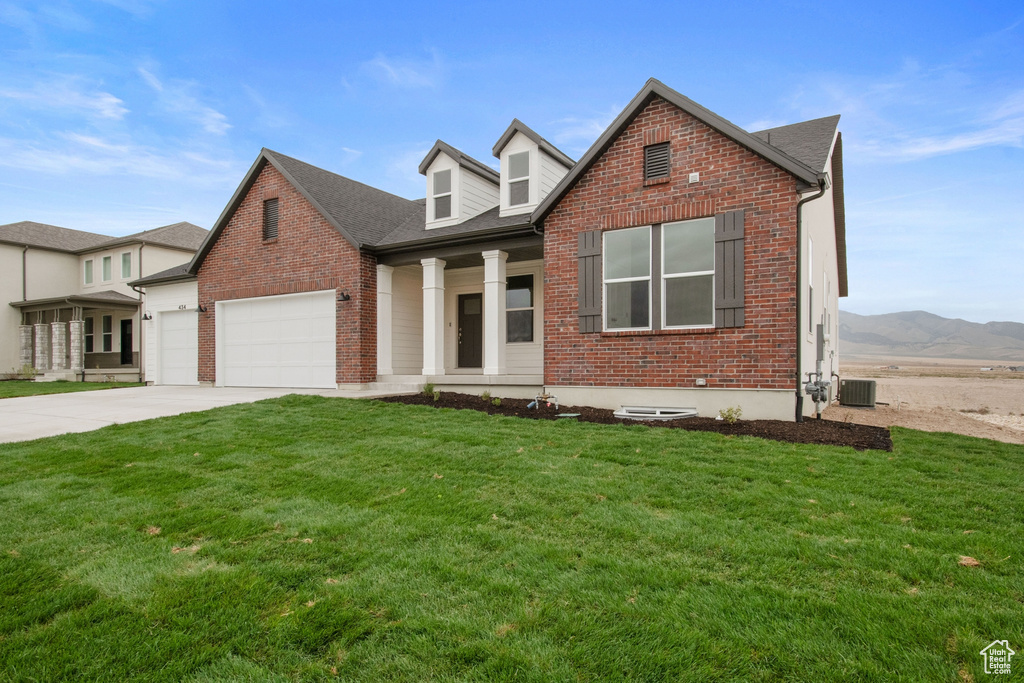 View of front of home with an attached garage, a mountain view, a front yard, brick siding, and driveway