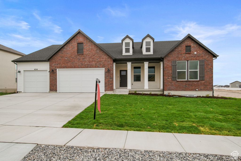 View of front of property with covered porch, a front yard, a garage, and driveway