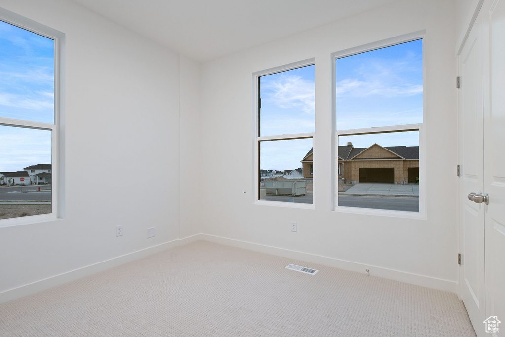 Unfurnished room with visible vents, baseboards, and light carpet
