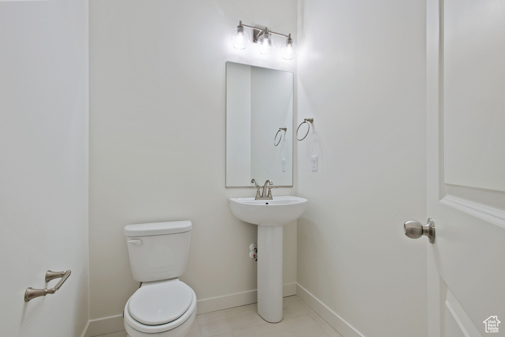 Half bath with toilet, baseboards, and tile patterned floors