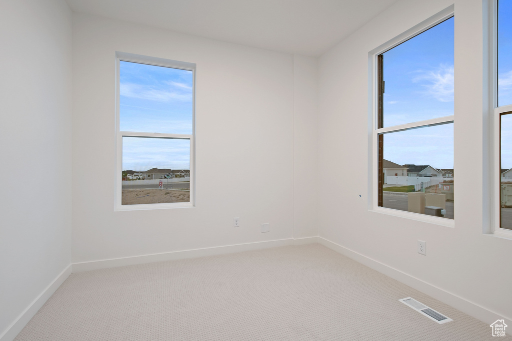 Spare room featuring plenty of natural light, visible vents, and light carpet