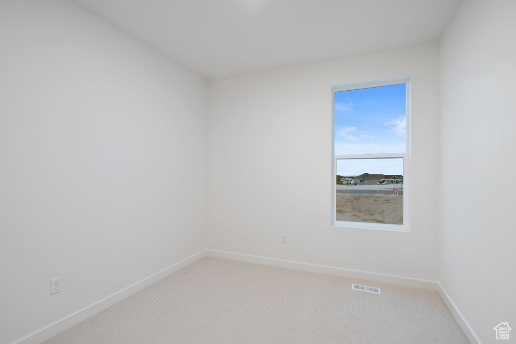 Empty room featuring light colored carpet, baseboards, and visible vents