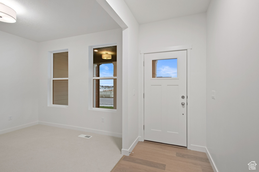 Foyer with baseboards, light wood finished floors, and visible vents