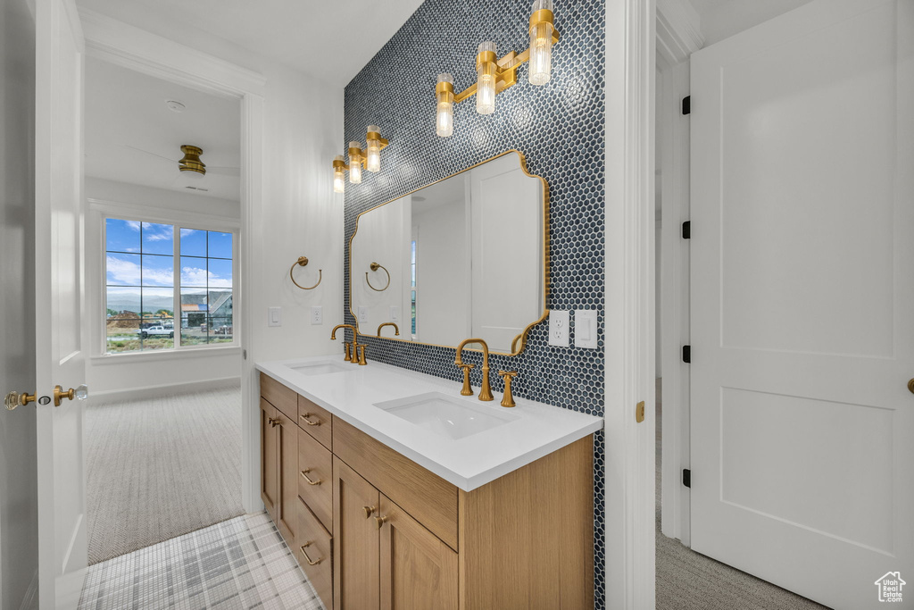 Full bath featuring double vanity, backsplash, and baseboards