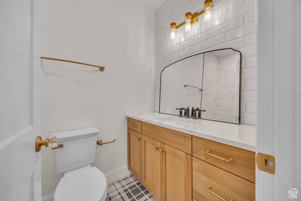Bathroom featuring toilet, baseboards, tile patterned flooring, and vanity