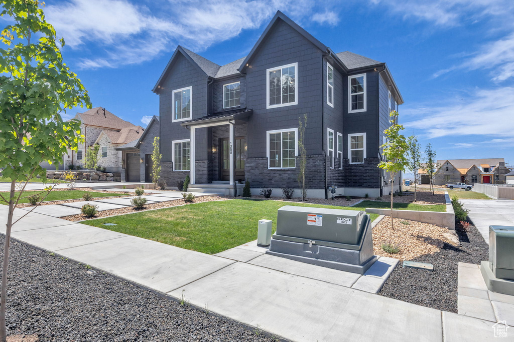 Traditional home featuring a front lawn, brick siding, and a residential view