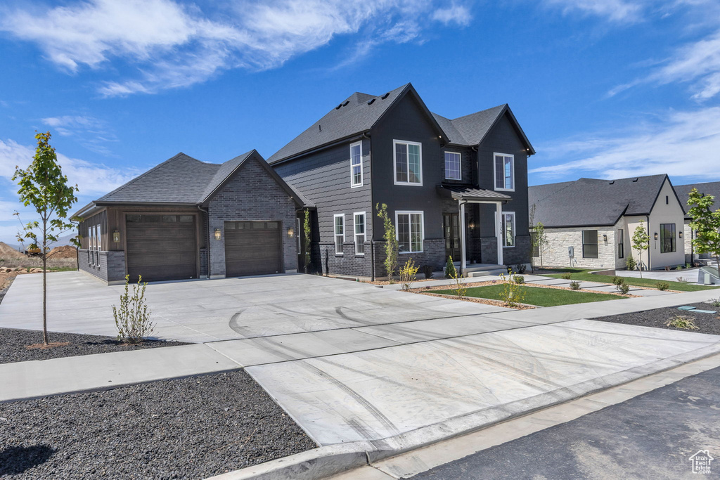 View of front of home with driveway, brick siding, and an attached garage