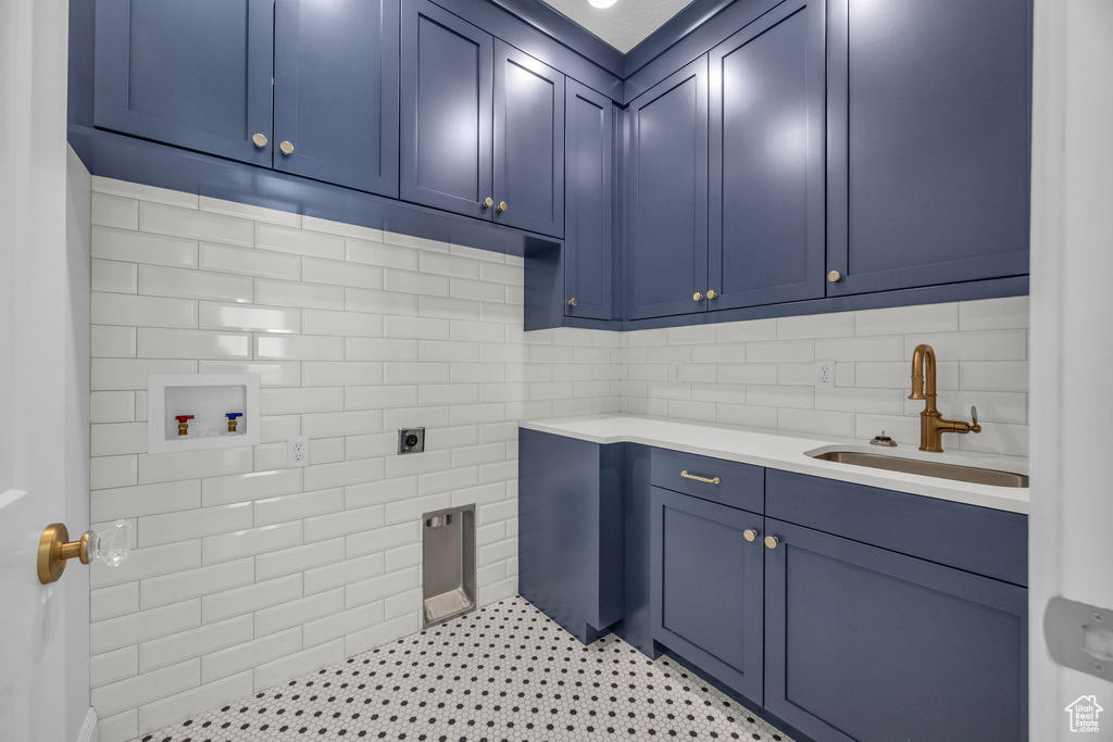 Clothes washing area with a sink, electric dryer hookup, washer hookup, and cabinet space