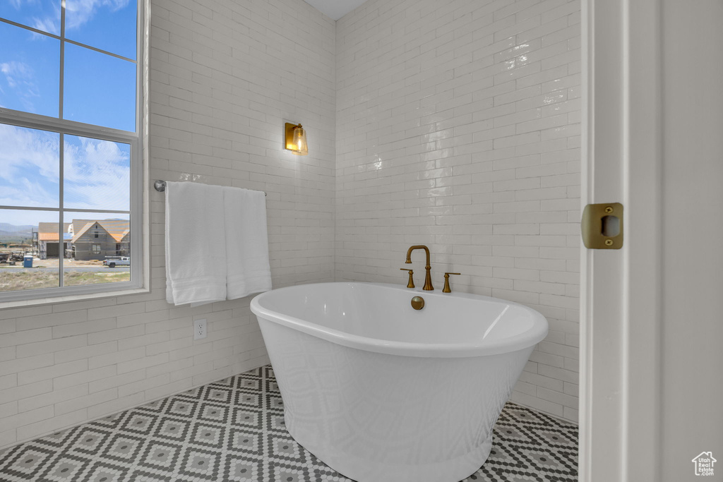 Bathroom featuring a soaking tub, tile walls, and tile patterned floors