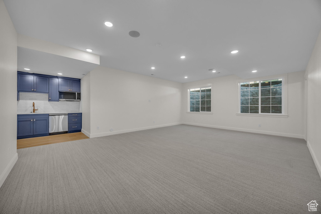 Unfurnished living room with light carpet, baseboards, and recessed lighting