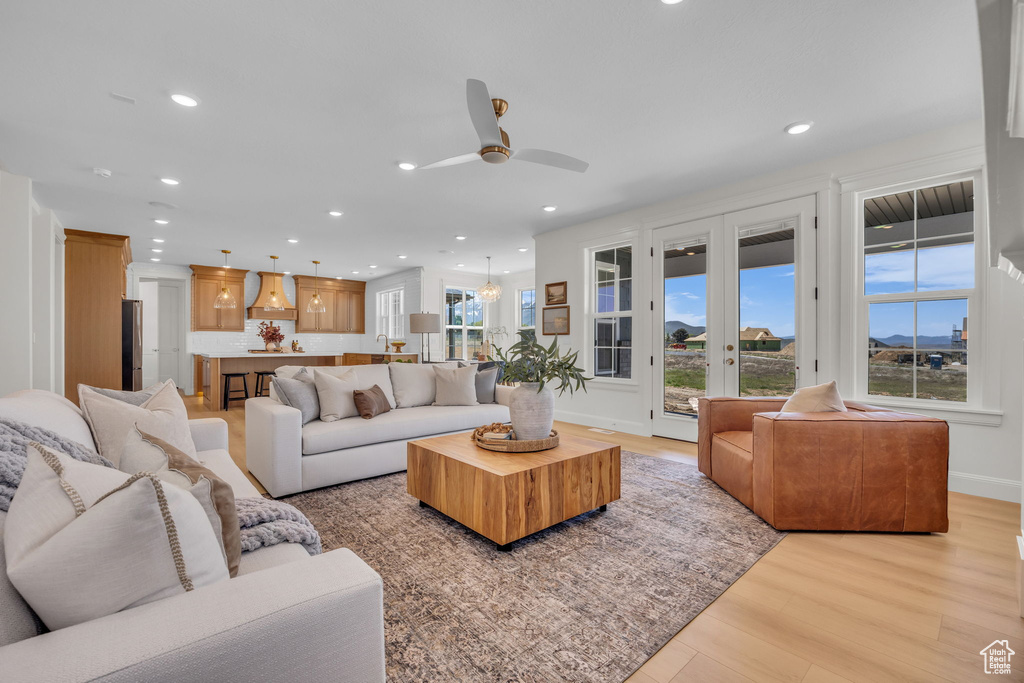 Living area featuring ceiling fan, baseboards, light wood finished floors, and recessed lighting
