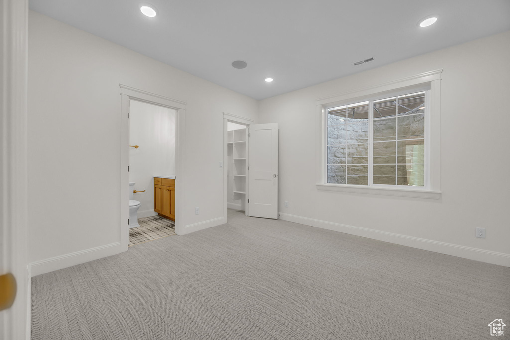 Unfurnished bedroom with recessed lighting, baseboards, visible vents, a walk in closet, and light colored carpet