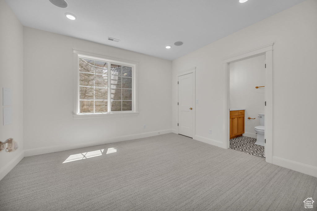Unfurnished bedroom featuring ensuite bathroom, carpet floors, baseboards, and visible vents