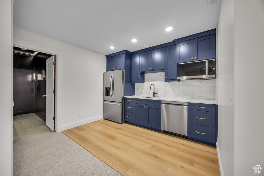 Kitchen featuring a sink, blue cabinets, stainless steel appliances, and light countertops