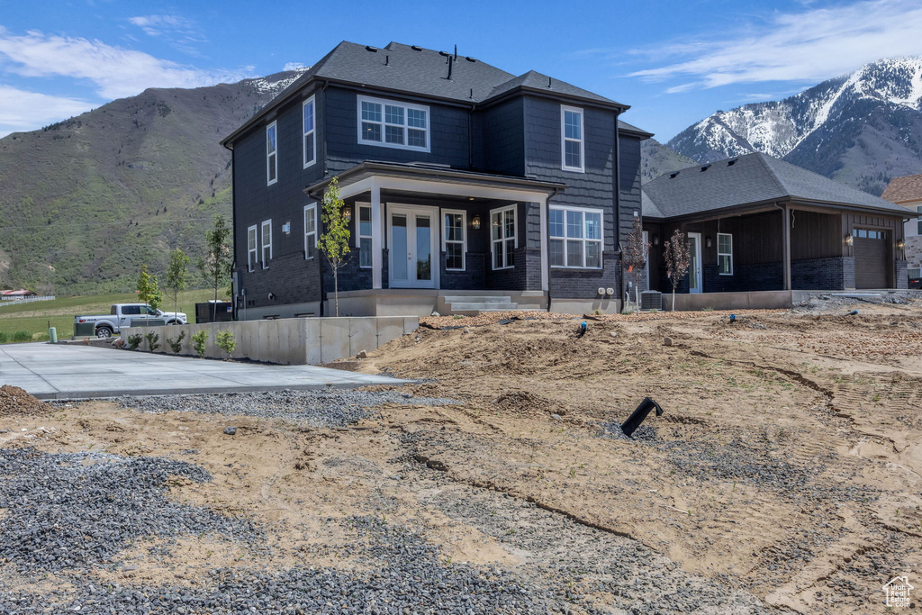 Back of property with a mountain view, french doors, and cooling unit