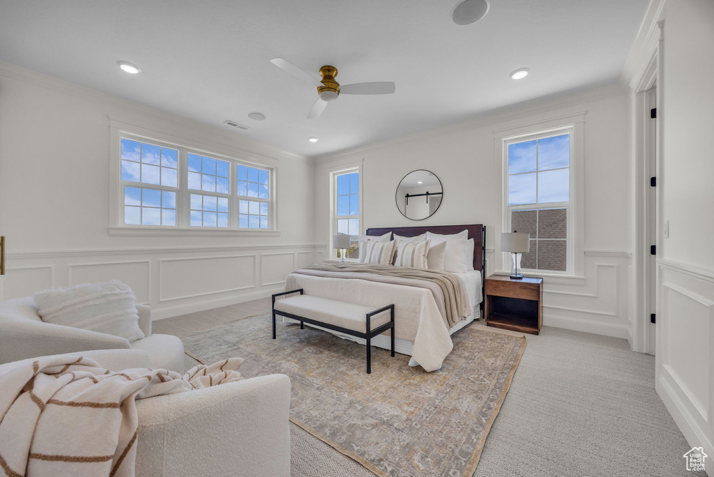 Carpeted bedroom with ornamental molding, a decorative wall, and wainscoting