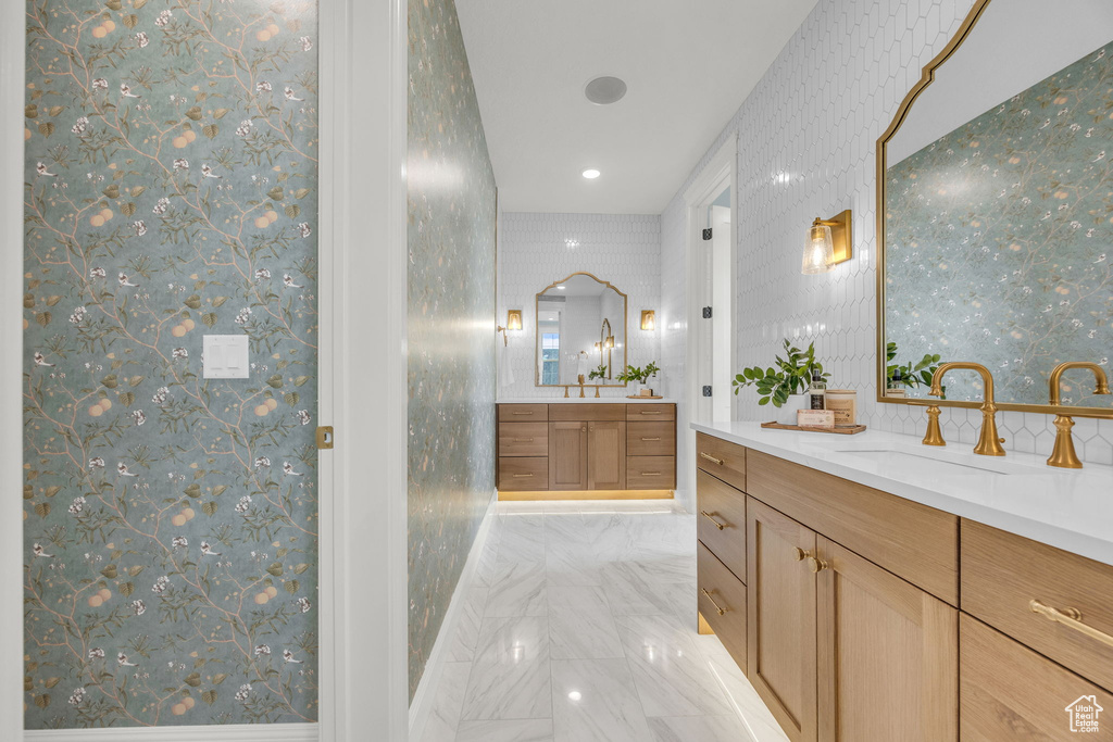 Bathroom featuring wallpapered walls, two vanities, and recessed lighting
