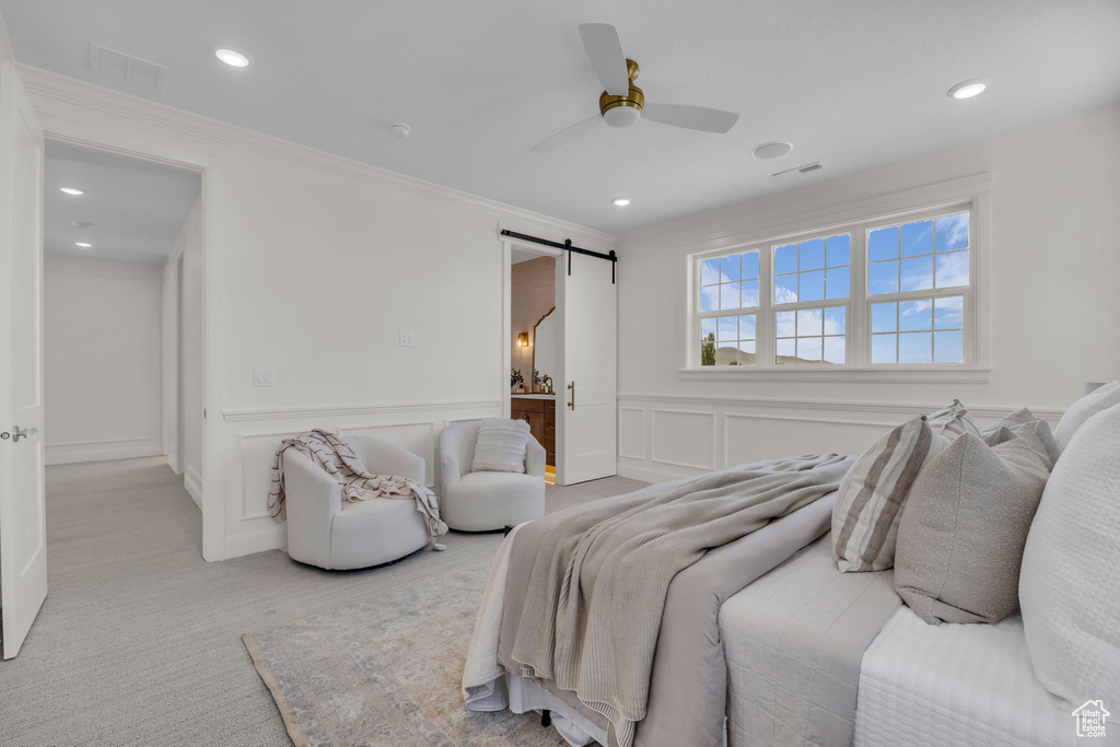 Bedroom featuring visible vents, a decorative wall, a barn door, ornamental molding, and recessed lighting