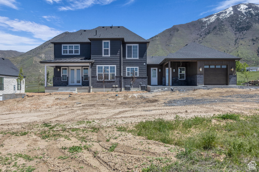 View of front of home with board and batten siding, brick siding, a mountain view, dirt driveway, and a garage