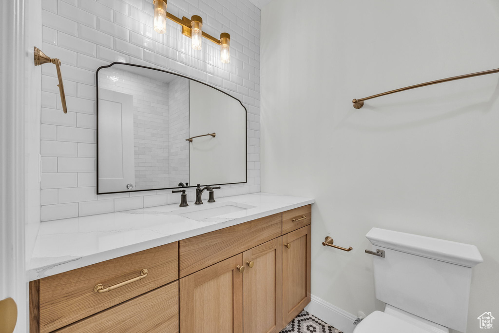 Bathroom featuring toilet, vanity, backsplash, and baseboards