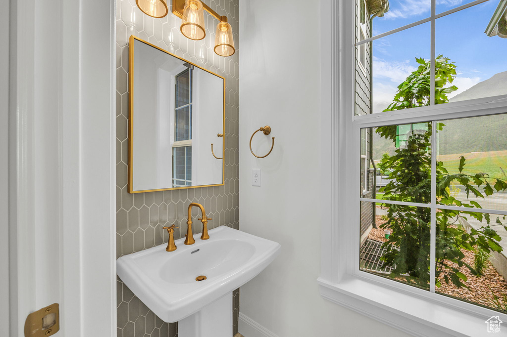Bathroom featuring a sink, decorative backsplash, and tile walls