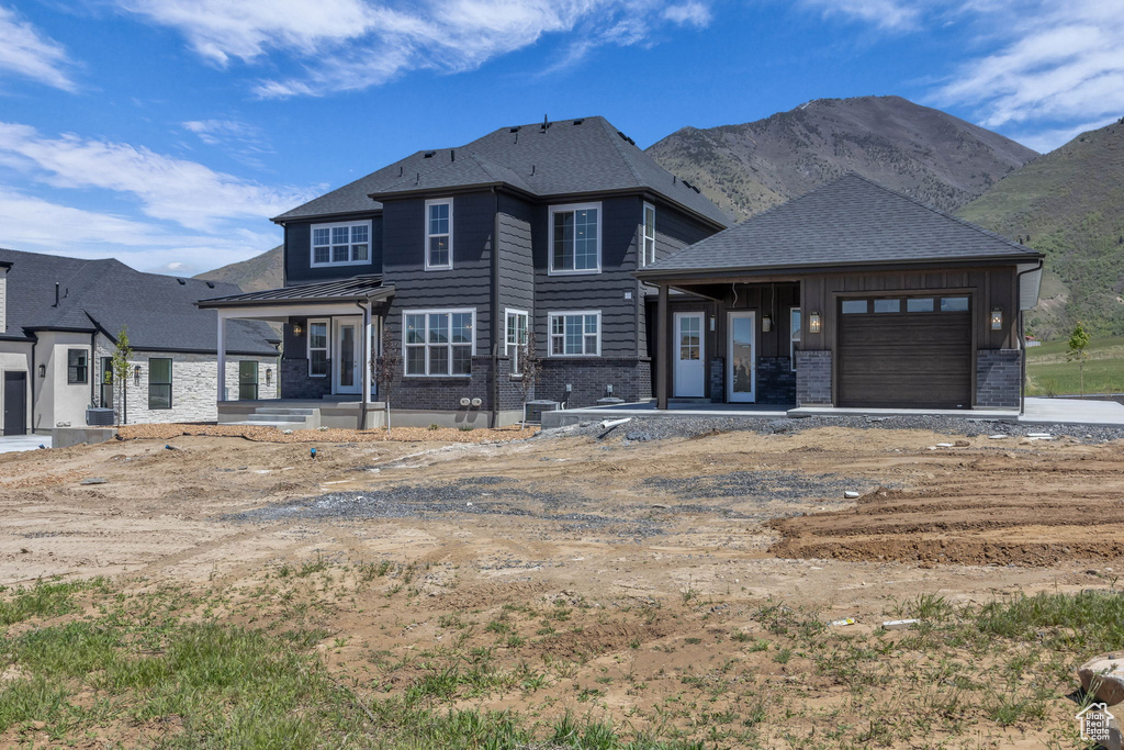 View of front of property featuring cooling unit, a mountain view, brick siding, and a garage