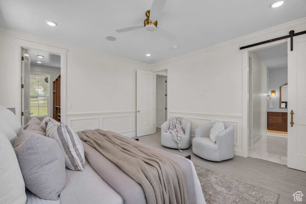 Bedroom with a decorative wall, light colored carpet, a barn door, and recessed lighting