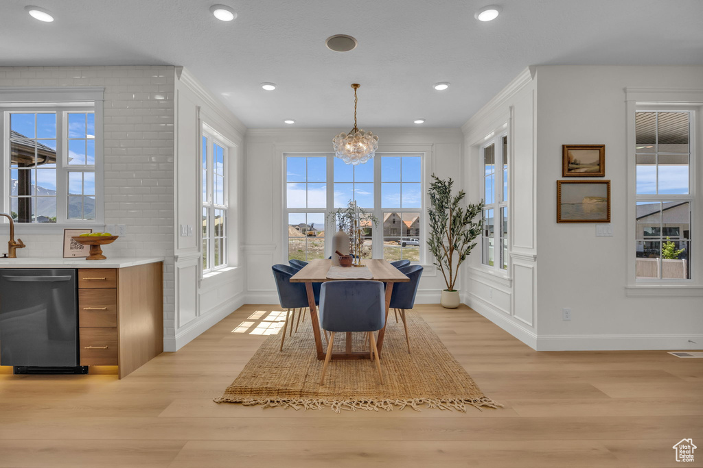 Dining room with a chandelier, a decorative wall, and light wood-style floors