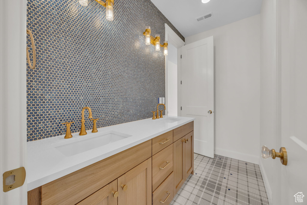 Bathroom with double vanity, visible vents, baseboards, and a sink