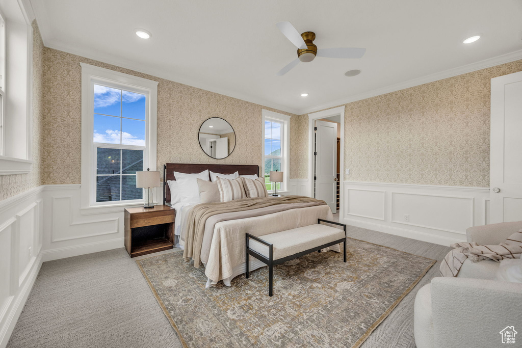 Bedroom with wallpapered walls, a wainscoted wall, ornamental molding, a decorative wall, and ceiling fan