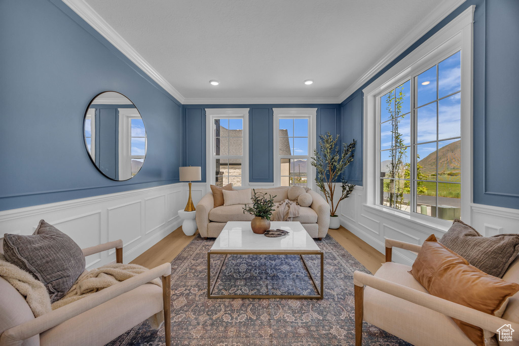 Living room with a wainscoted wall, light wood-type flooring, a decorative wall, and ornamental molding