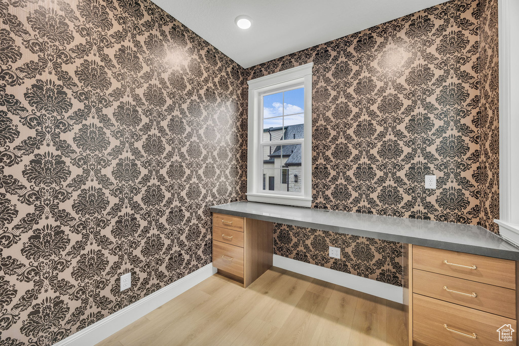 Bathroom with wood finished floors, baseboards, and wallpapered walls