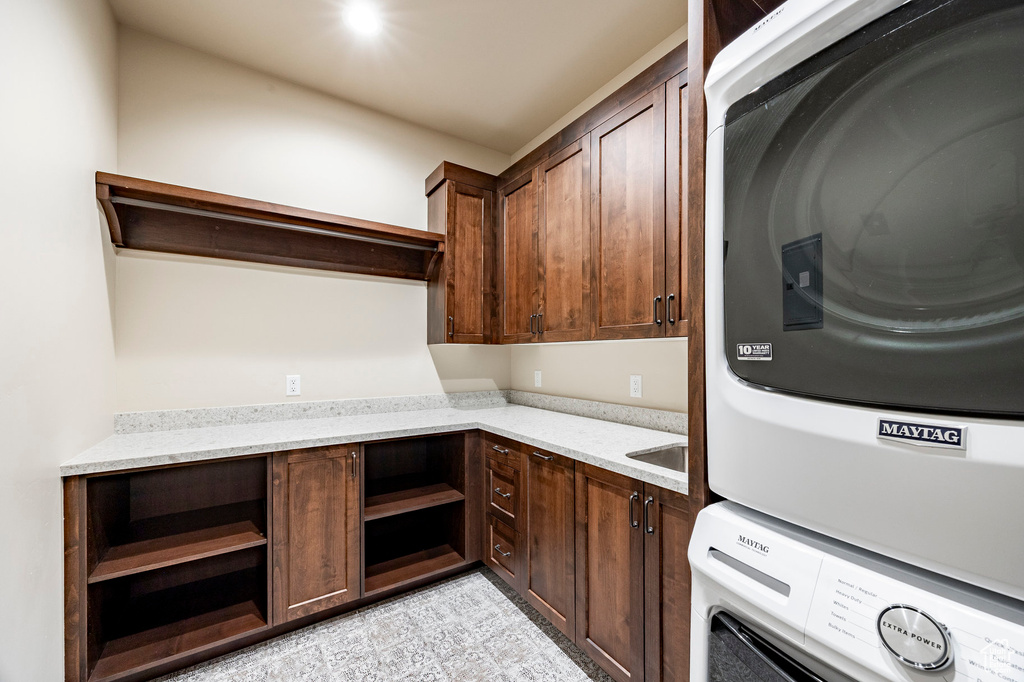 Washroom featuring stacked washer / dryer and cabinet space