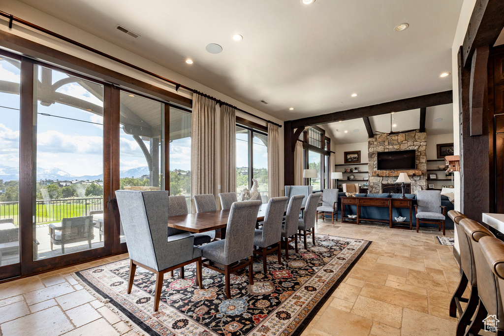 Dining area with a mountain view, a fireplace, stone tile floors, visible vents, and recessed lighting