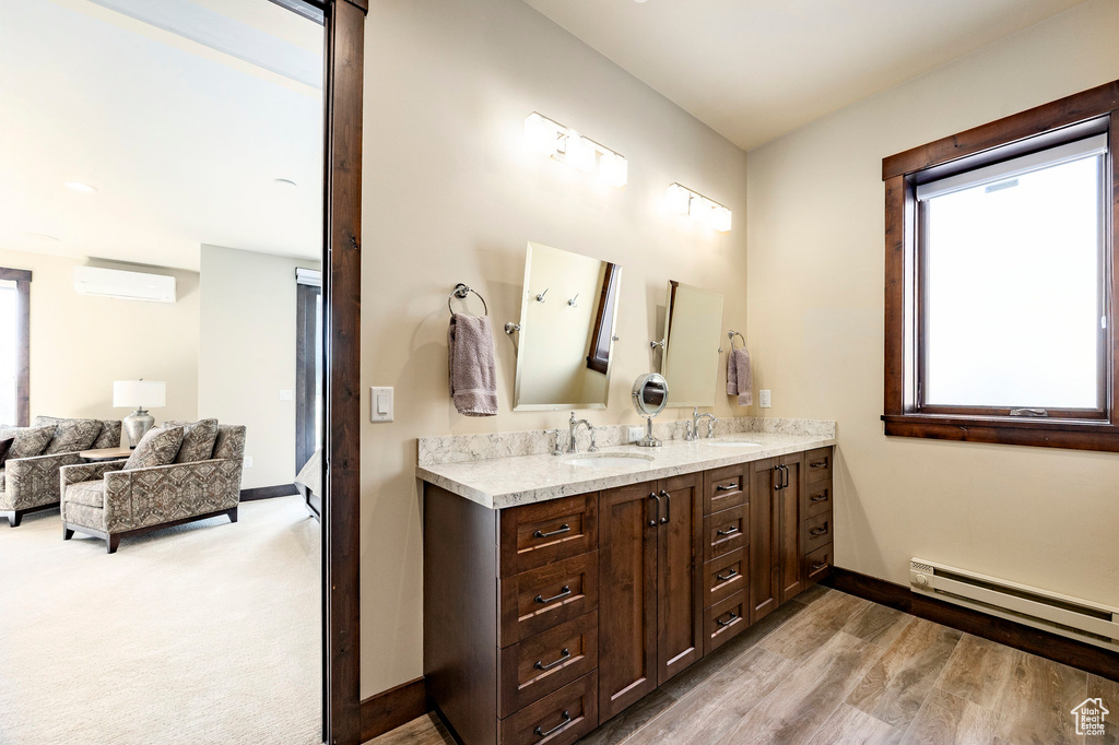 Full bathroom with a sink, a wall mounted air conditioner, baseboards, and a baseboard heating unit