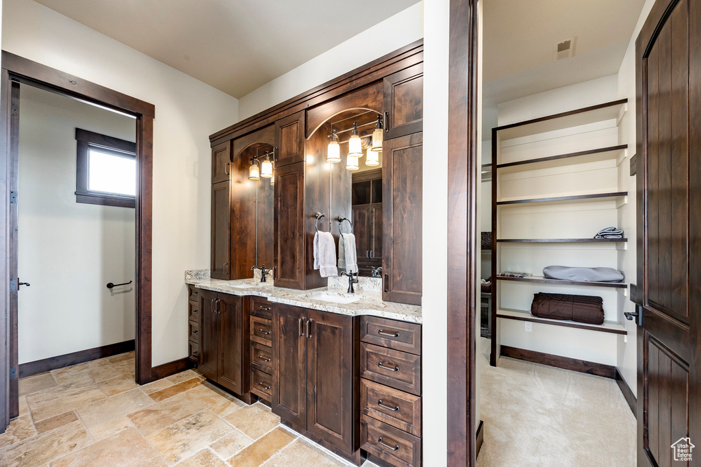 Full bath with a sink, double vanity, baseboards, and visible vents