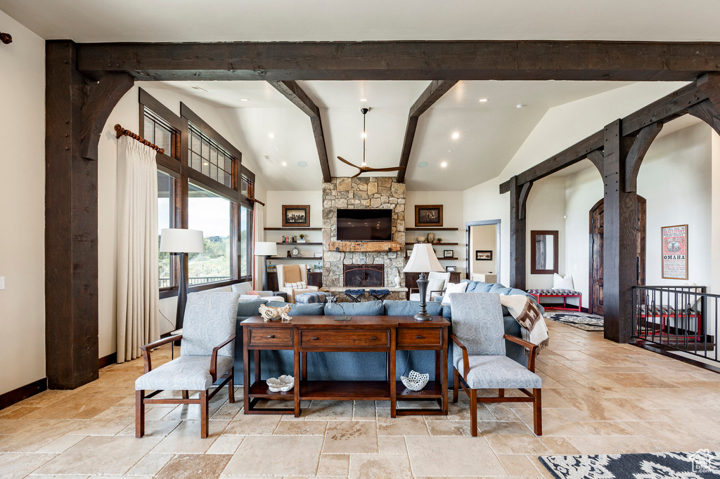 Living room with stone tile flooring, baseboards, arched walkways, a fireplace, and beam ceiling